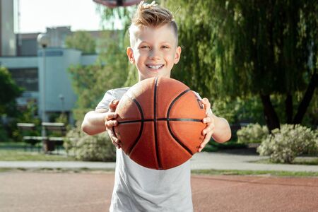 Portrait of a boy with a basketball on a basketball court. The concept of a sports lifestyle, training, sport, leisure, vacationの写真素材