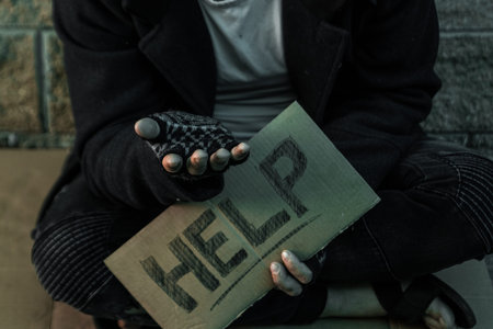 A man, homeless, a person asks for alms on the street with a Help sign. Concept of homeless person,...