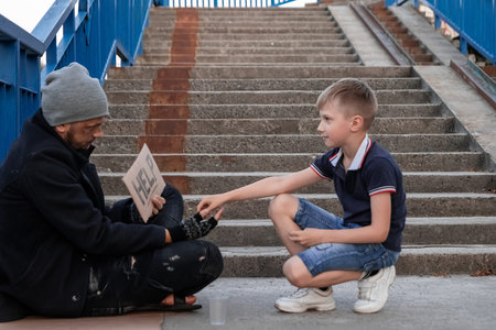The boy helps the homeless on the street. Concept of a homeless person, social problem, addict,...