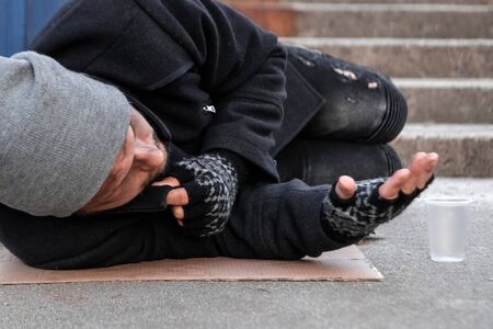 A man, homeless, a person asks for alms on the street with a Help sign. concept of homelessness, social problem, drug addict, poverty, despairの写真素材