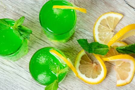 Green stemware shot alcoholic cold cocktail with cranberries raspberries lemon and mint. Selective focus, copy space.の写真素材