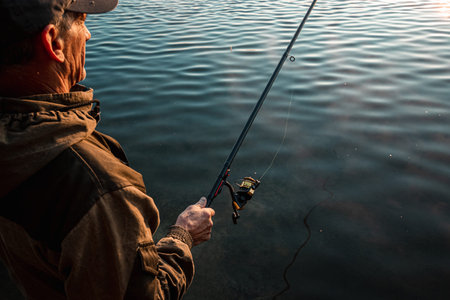 A male fisherman on the lake is standing in the water and fishing for a fishing rod.