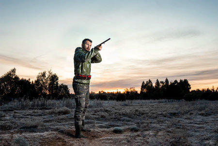 Hunter man in camouflage with a gun during the hunt in search of wild birds or game on a beautiful...
