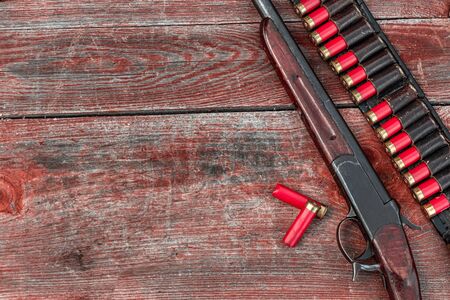 Shotgun and cartridges in patronage are lying on a wooden table top view. The hunting period, the season is openの写真素材