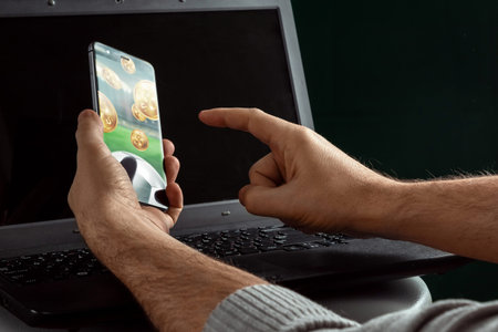 Smartphone in hand Sports Betting on laptop background. Bets, sports betting, bookmaker. Mixed...