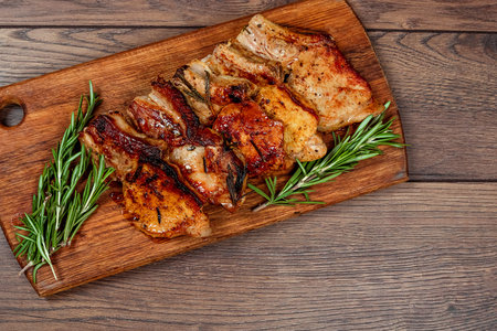 Pork steak and sprig of rosemary on a wooden cutting board. Recipe, cooking meat