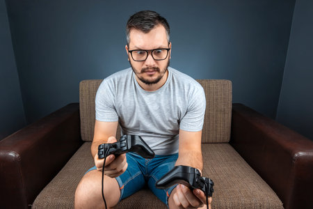 A man plays a video game console while sitting on a sofa. Day off, entertainment, leisure