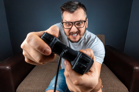 A man plays the console, video games react strongly and emotionally while sitting on the couch. Day...