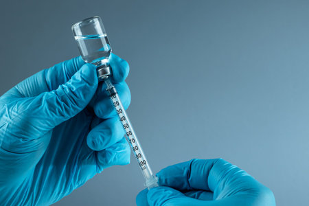 Hand holding syringe Vaccine in vial closeup on gray background, medical concept vaccination...