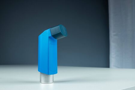 An asthma inhaler lies on a white table against a gray background, an asthmatic attack. The concept of treatment of bronchial asthma, cough, allergies, dyspneaの写真素材