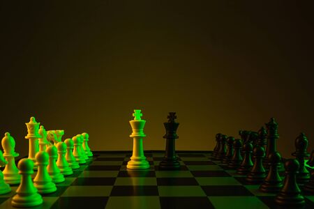 Chess pieces on a chessboard, game, Confrontation of kings. Yellow green neon color. The concept of confrontation, career, competition, startupの写真素材