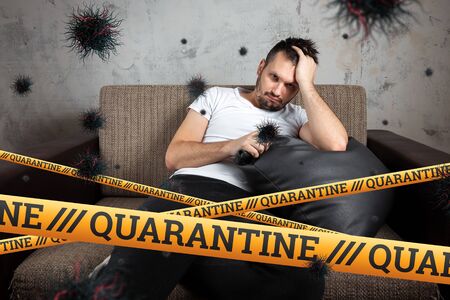 Quarantine Barrier yellow forbidden tape, isolation. Coronavirus. A man sits at home on a self-isolating particle of the COVID-19 virus. The concept is boringの写真素材