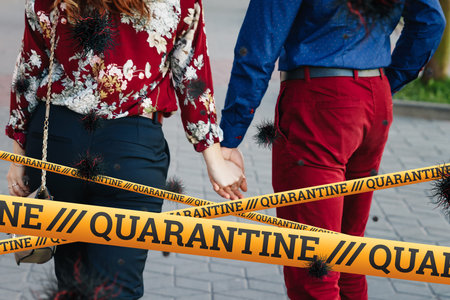 Quarantine Barrier yellow forbidden tape, isolation. Couple holding hands on the street and...
