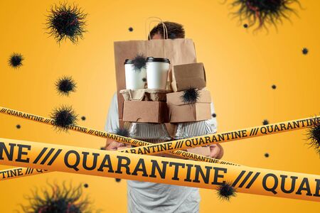 Quarantine Barrier yellow forbidden tape, isolation. Delivery courier in a protective mask and particles of the virus COVID-19. Concept Delivery of goods for the prevention of coronovirusの写真素材