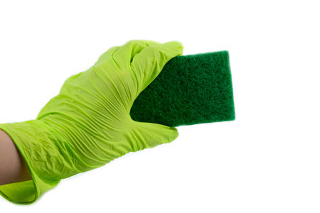 Sponge for dishes in a female hand in a green glove isolated on a white background. Copy space