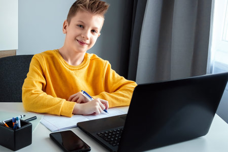Distance learning, a boy learns math while looking at a laptop beech during an online lesson. The...