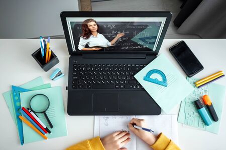 Distance learning, top view boy sitting at a table at home looking in a beech laptop. The concept of online education, home education, technology, schoolの写真素材