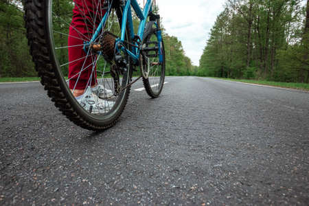 Legs on the pedals of a bicycle close-up, riding a road in the forest. The concept of a healthy lifestyle, cardio training. Copyspaceの写真素材