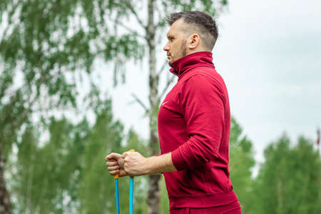 Sports, outdoor activities, Nordic walking, a man with sticks close-up. The concept of a healthy lifestyle, cardio training. Copyspaceの写真素材