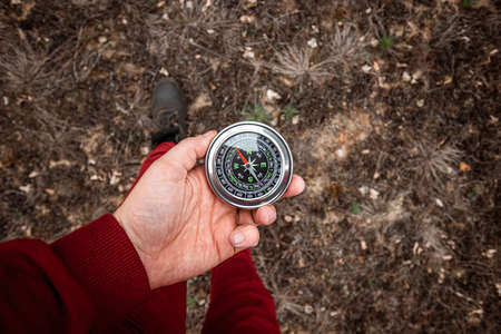 Compass in hand on a background of legs, Close-up. The concept of travel, hiking, vacation. Copy spaceの写真素材
