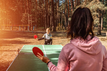 A boy plays table tennis  with his mom, sports games. The concept of family ties, intergenerational...