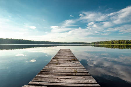 Wooden pier on the background of a beautiful lake summer dawn landscape. Copy spaceの写真素材