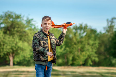 The boy launches a toy airplane against the backdrop of greenery. The concept of dreams, choice of...