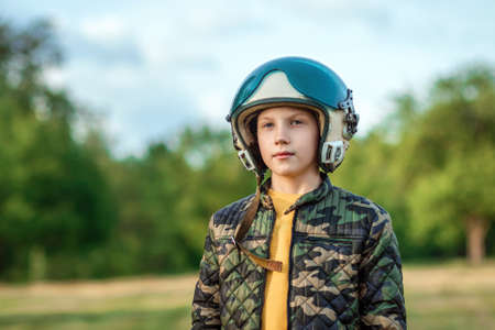 A boy in a pilot's helmet on a background of greenery. Dream concept, choice of profession, game. Copy spaceの写真素材