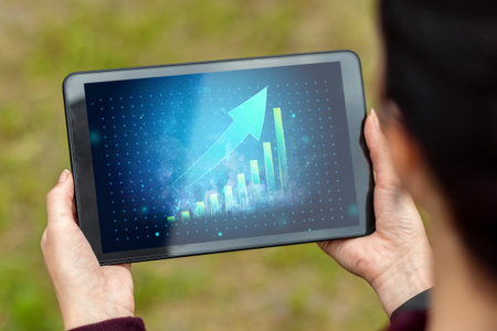 Close-up of a tablet in hands with the image of a graph with an upward arrow. New technologies. Copy...