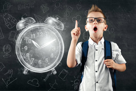 Time management concept, schoolboy with a backpack and near the image of an alarm clock. Time is...