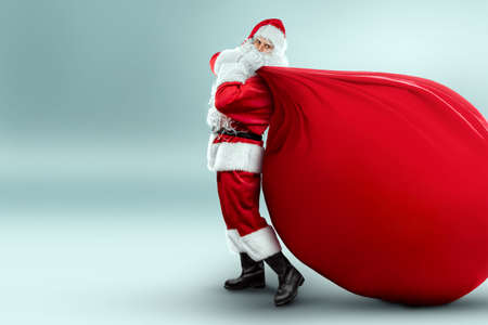 Portrait of a cheerful Santa Claus in a red suit carries a big bag, light background. Concept for christmas eve, vacation, holiday banner, new year. 3D illustration, 3D renderの写真素材