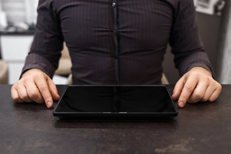 Black tablet with blank screen and male hands on the table, top view. Concept businessman, office, financeの写真素材