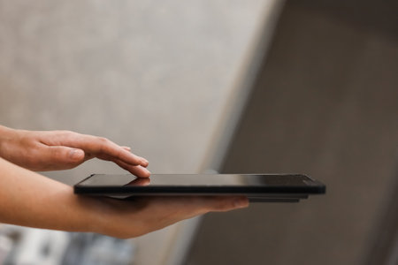 A female hand presses on the screen of a digital tablet close-up, side view. New technology concept, multimediaの写真素材
