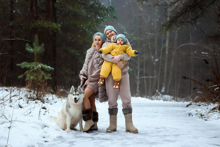 Happy family Dad, mom and baby sy on a winter walk in the forest. Concept for christmas, family, relatives, vacations, fresh airの写真素材