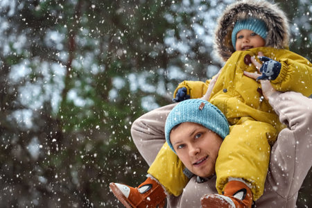 Happy family Dad and baby sy on a winter walk in the forest. Concept for christmas, family,...