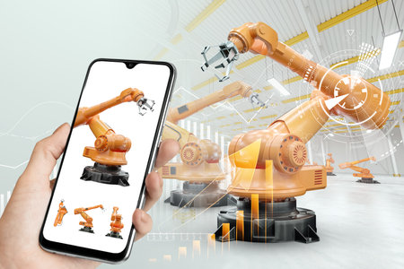Smartphone in a man's hand and robotic arms of a modern plant. Iot technology concept, smart factory. Digital manufacturing operation. Industry 4.0.の写真素材