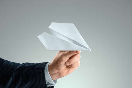 A man's hand in a business suit holds a paper airplane. Startup concept, light business, getting started. Copy spaceの写真素材