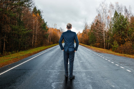 A businessman in a business suit stands on the road, a long way in front. Development concept, start-up, investment searchの写真素材