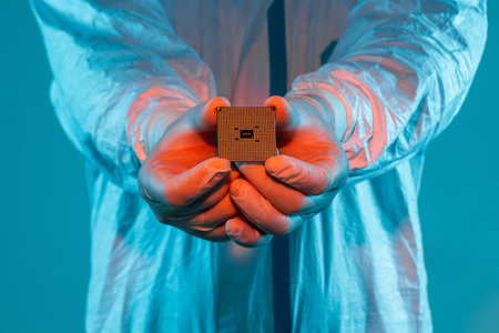 A man in sterile form holds a microprocessor, close-up. Microchip production technology, modern...