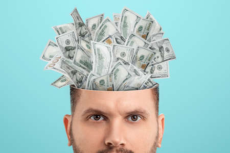Business thinking, money, dollars sticking out of the mind of a man instead of a brain. Creative background, business concept, entrepreneurship, startupの写真素材