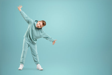 Little in a turquoise suit poses and fools around on a turquoise background, looks at the camera....
