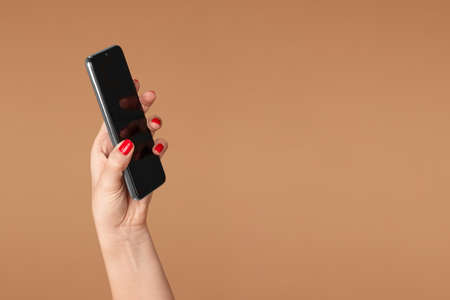 In a female hand a smartphone on a beige backgroundの写真素材