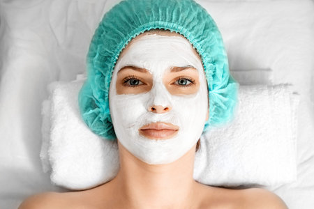 The girl's face covered with a cosmetic mask, close-up. Skin care, beautician, spa treatments, facial hygieneの写真素材