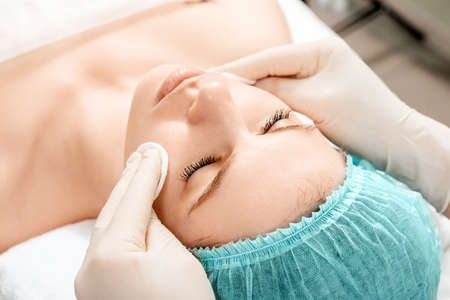 The girl's face is being cleaned after spa procedures, close-up. Skin care, beautician, spa treatments, facial hygieneの写真素材