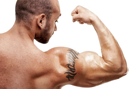 Tattooed male bodybuilder posing over white background. Fitness workout concept, muscle groups, watch your bodyの写真素材