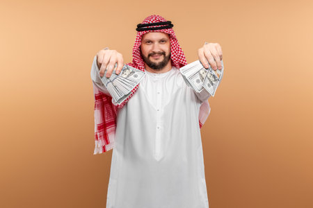 Arab man businessman in national clothes is holding dollars in his hands. Business concept in the...