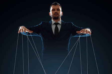 Male, puppeteer controls with threads. The concept of world conspiracy, world government, manipulation, world controlの写真素材