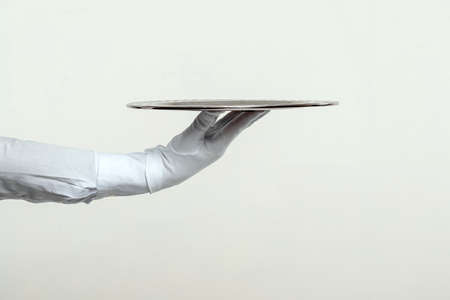 The waiter's hand in white gloves holds a silver tray. Isolate on a light backgroundの写真素材