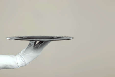 The waiter's hand in white gloves holds a silver tray. Isolate on a light backgroundの写真素材