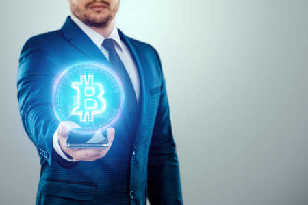 Bitcoin coin in the hand of a businessman, hologram. Digital currency, virtual money, and cryptocurrency, blockchain technologyの写真素材